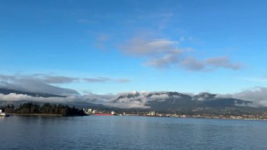 Mavi gökyüzünün altındaki bulutlarda gizlenmiş puslu dağlar dingin ve gizemli bir doğal manzara yaratır.. 