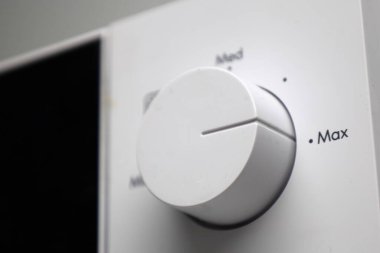 rotary knob on a microwave oven with power settings: min, med, max. sleek white casing, modern design, and a simple, user-friendly control interface. clipart