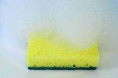 Beyaz-mavi arka planda sarı-yeşil bulaşık süngeri, yakın plan, temizlik aksesuarı, mutfak hijyen aracı