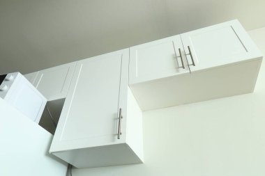 Beyaz mutfak dolapları, buzdolabının üstünde mikrodalga fırın, minimalist iç mekan, temiz ve basit tasarım..