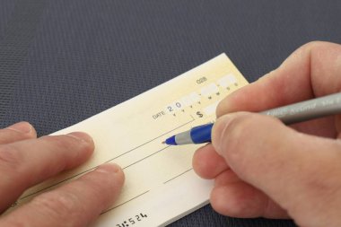 Banka çekini koyu bir geçmişi olan mavi kalemle dolduran yakın plan mali konsept..