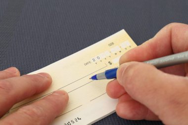 Banka çekini koyu bir geçmişi olan mavi kalemle dolduran yakın plan mali konsept..