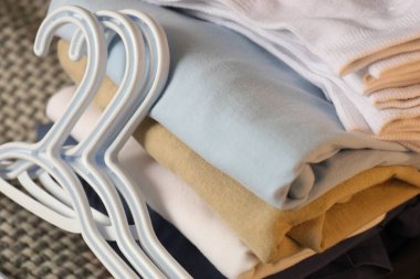 Katlanmış giysiler, beyaz çoraplar ve halının üzerindeki plastik askılar gardırobu düzenlemeye hazırlanıyor.