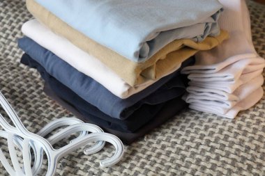 Katlanmış giysiler, beyaz çoraplar ve halının üzerindeki plastik askılar gardırobu düzenlemeye hazırlanıyor.