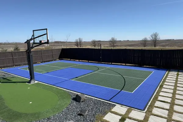 Basketbol ve mini golf sahası olan modern bir arka bahçe, açık bir alana ve temiz gökyüzüne bakıyor..