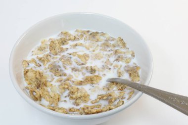 Bir kase sütlü mısır gevreği, bir insan bir kaşık tutuyor..