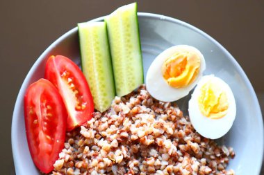 Haşlanmış yumurtalı karabuğday, salatalık ve domates sağlıklı ve dengeli bir yemek..