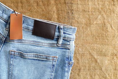 İple tutturulmuş beyaz etiketli mavi yıkanmış kot pantolonlara yakın plan. Moda ve perakende kavramları için günlük kıyafet ayrıntıları.