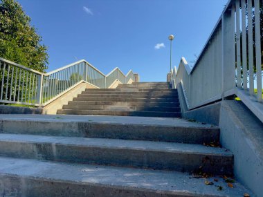 Açık havada beton merdivenler, açık mavi gökyüzünün altından yukarıya doğru uzanan metal parmaklıklar, ilerlemeyi, başarıyı ve yeni fırsatlara giden yolu simgeliyor..