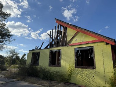 Clarksville, TN, USA - October 3, 2024: Exterior view of a dilapidated house destroyed by a tornado, with missing roof and broken windows surrounded by overgrown vegetation clipart