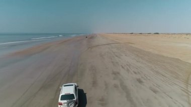 Pasni plajı ıslak kumda sıkıştı. Sahilde bir cip. Arabalarla deniz kıyısına yolculuk. Pasni plajına tur.