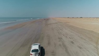 Pasni plajı ıslak kumda sıkıştı. Sahilde bir cip. Arabalarla deniz kıyısına yolculuk. Pasni plajına tur.