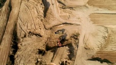 Kazıcının ezilmiş taşları bir çöp kamyonuna yüklediği görüntü. Üst Hava Görünümü