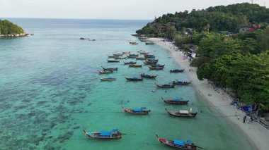 Tropik bir ada cennetinin havadan görünüşü. Ada kristal berraklığında turkuaz sularla ve el değmemiş beyaz kumsalla çevrilidir. Birçok geleneksel uzun kuyruklu tekne kıyıya yanaştı.