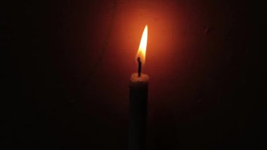 Karanlıkta yanan bir mum videosu sessizlik ve yalnızlık atmosferini ima eder.