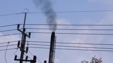 Fabrika bacası siyah duman yayıyor.