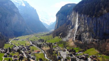 A mesmerizing 4K drone shot of a waterfall cascading down rugged cliffs into a tranquil valley below. The rushing water contrasts beautifully with the lush greenery and serene surroundings. clipart