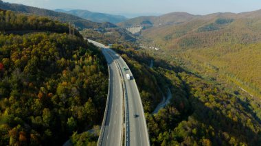 Dar vadi yolları boyunca kıvrılan, yemyeşil ve yuvarlanan tepelerle çevrili, dinamik bir 4K hava manzarası. Virajlı yollar resmedilmeye değer doğal manzarayla uyum içinde..