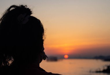 Brighton sahilinde gün batımını izleyen bir kadın.