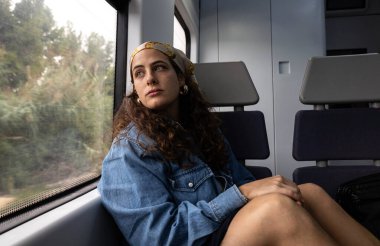 Trenin penceresinden manzaraya bakan kadın pencereye yaslanmış.