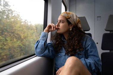 Trenin penceresinden manzaraya bakan bir kadın yüzünde tasasız bir ifadeyle..