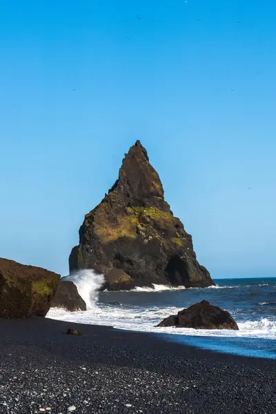 stock image The dramatic Reynisfjara Beach features black volcanic sands and towering basalt sea stacks rising from the wild Atlantic Ocean in Iceland