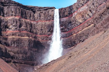 Doğu İzlanda 'daki Hengifoss şelalesine giden yolun çarpıcı manzarası, engebeli kayalıklar ve bazalt sütunlarla çevrili. Şelale gibi akan su sakin bir vadiye akıyor, nefes kesici manzaralar sunuyor ve Ic 'i keşfeden yürüyüşçülere ödüllendirici bir deneyim sunuyor.