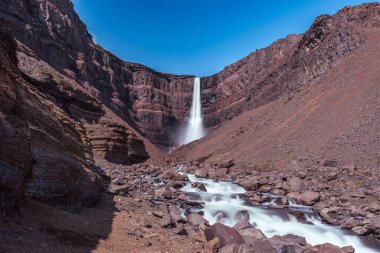 Doğu İzlanda 'daki Hengifoss şelalesine giden yolun çarpıcı manzarası, engebeli kayalıklar ve bazalt sütunlarla çevrili. Şelale gibi akan su sakin bir vadiye akıyor, nefes kesici manzaralar sunuyor ve Ic 'i keşfeden yürüyüşçülere ödüllendirici bir deneyim sunuyor.