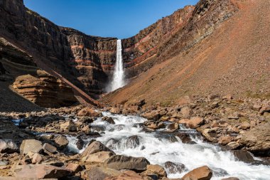 A stunning view of the trail leading to Hengifoss waterfall in East Iceland, surrounded by rugged cliffs and basalt columns. The cascading water flows into a serene gorge, offering breathtaking views and a rewarding experience for hikers exploring Ic clipart