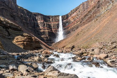 Doğu İzlanda 'daki Hengifoss şelalesine giden yolun çarpıcı manzarası, engebeli kayalıklar ve bazalt sütunlarla çevrili. Şelale gibi akan su sakin bir vadiye akıyor, nefes kesici manzaralar sunuyor ve Ic 'i keşfeden yürüyüşçülere ödüllendirici bir deneyim sunuyor.