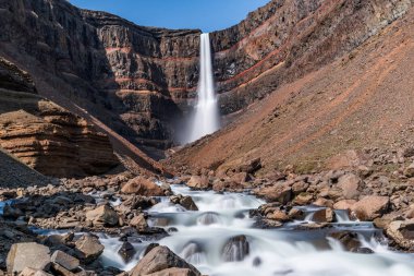 Doğu İzlanda 'daki Hengifoss şelalesine giden yolun çarpıcı manzarası, engebeli kayalıklar ve bazalt sütunlarla çevrili. Şelale gibi akan su sakin bir vadiye akıyor, nefes kesici manzaralar sunuyor ve Ic 'i keşfeden yürüyüşçülere ödüllendirici bir deneyim sunuyor.