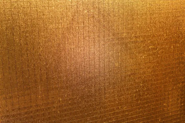 stock image Close-up of a textured golden surface with grid lines, creating a luxurious and shiny metallic pattern. Ideal for backgrounds, wallpapers, or creative design projects.