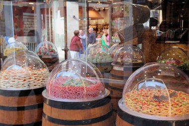 Ahşap varillerin tepesindeki cam kubbelerde renkli şeker ve şekerlerin canlı bir gösterisi. Müşteriler pencereden gelen zevkli ikramlara hayran kalarak, davetkar ve şenlikli bir atmosfer yaratıyorlar..