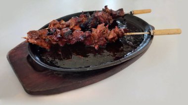 Ahşap saplı demir şiş ile pişirilmiş sığır eti. Elektrikli ocakta.