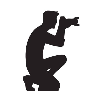 Çömelmiş bir pozisyonda bir fotoğrafçıyı gösteren silüet bir görüntü. Düşük bir açıdan bir görüntü yakalıyor. Profesyonel fotoğrafçılığı ve benzersiz bakış açılarını çağrıştırıyor..