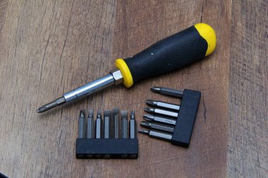 Ahşap efekt arka planında çeşitli parçaları olan tornavida.