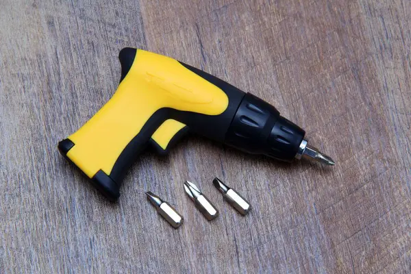 Tahta efekt arka planında çeşitli parçaları olan cırcır tornavidayı tetikle.