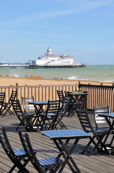 Gümüş kubbeli Eastbourne İskelesi plaj masaları ve ön planda sandalyeler ile altın rengine boyanmadan önce..