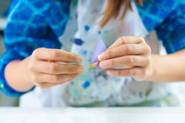 Çocuk roket yapmak için mor kağıt katlıyor..