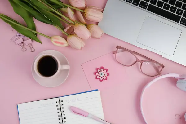 Pembe ofis aletleri, pembe kulaklık, not defteri, kalem ve pembe arka planda bir buket pembe lale fotokopi alanı konsepti.