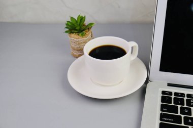 Bir fincan kahve, bir dizüstü bilgisayar ve bir defter, krema masasında gözlük. Eğitim, iş ve ofis kavramı. 