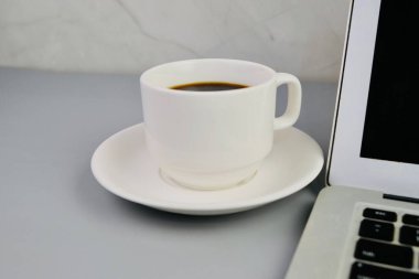 Bir fincan kahve, bir dizüstü bilgisayar ve bir defter, krema masasında gözlük. Eğitim, iş ve ofis kavramı. 