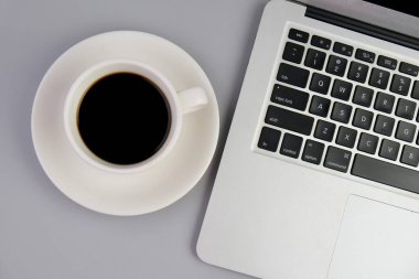 Bir fincan kahve, bir dizüstü bilgisayar ve bir defter, krema masasında gözlük. Eğitim, iş ve ofis kavramı. 