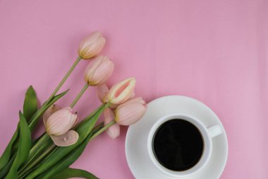 Pembe ofis aletleri, pembe kulaklık, not defteri, kalem ve pembe arka planda bir buket pembe lale fotokopi alanı konsepti.