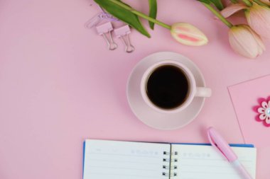 Pembe ofis aletleri, pembe kulaklık, not defteri, kalem ve pembe arka planda bir buket pembe lale fotokopi alanı konsepti.