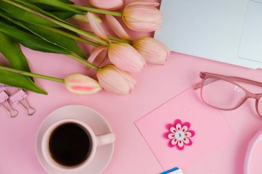 Pembe ofis aletleri, pembe kulaklık, not defteri, kalem ve pembe arka planda bir buket pembe lale fotokopi alanı konsepti.