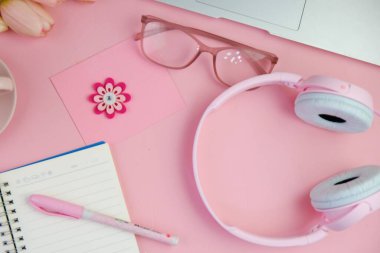 Pembe ofis aletleri, pembe kulaklık, not defteri, kalem ve pembe arka planda bir buket pembe lale fotokopi alanı konsepti.