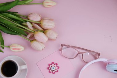 Pembe ofis aletleri, pembe kulaklık, not defteri, kalem ve pembe arka planda bir buket pembe lale fotokopi alanı konsepti.