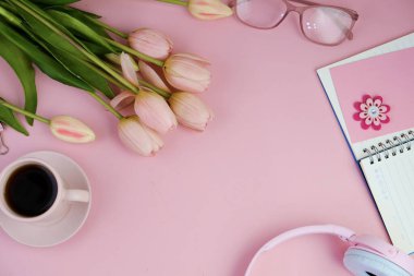 Pembe ofis aletleri, pembe kulaklık, not defteri, kalem ve pembe arka planda bir buket pembe lale fotokopi alanı konsepti.