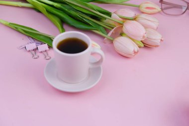 Pembe ofis aletleri, pembe kulaklık, not defteri, kalem ve pembe arka planda bir buket pembe lale fotokopi alanı konsepti.